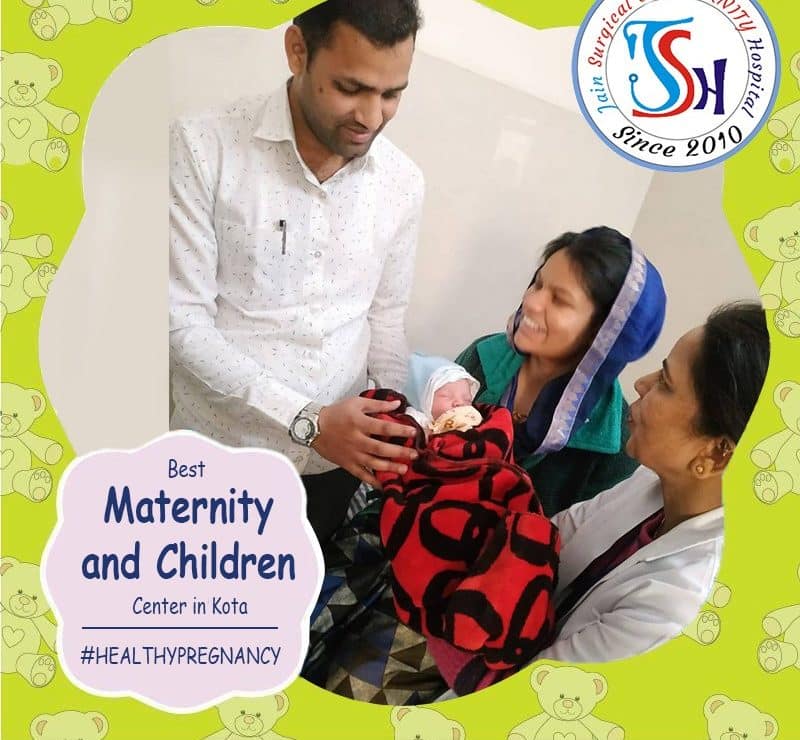 A woman holding a baby and a man holding a teddy bear at the best maternity hospital in Kota.